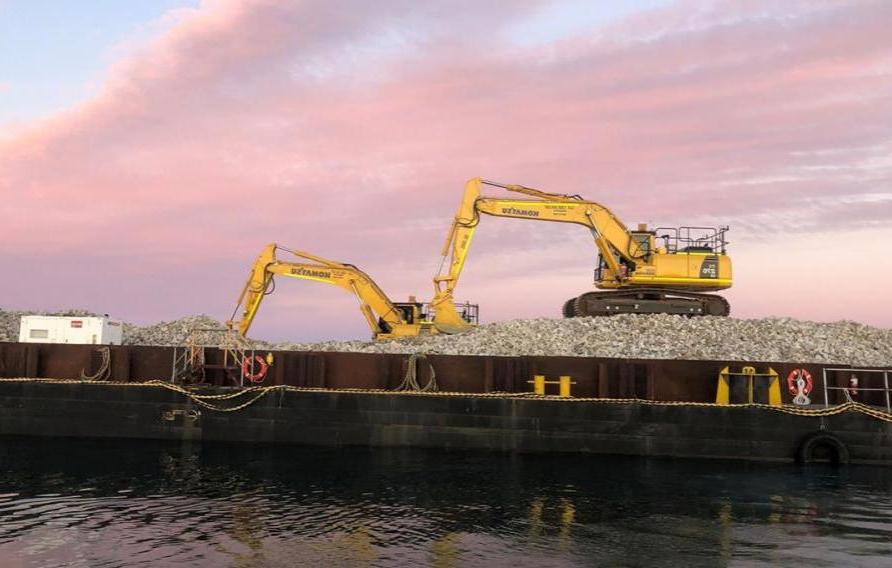 两台在温达拉礁施工的挖掘机，身后是夕阳下粉红色的天空