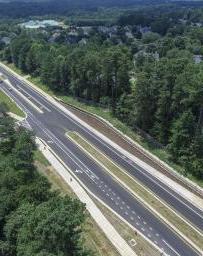 Aerial view of a two lane highway surrounded by green trees on both sides