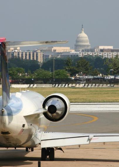 飞机降落在跑道上，背景是华盛顿特区的天际线，包括白宫